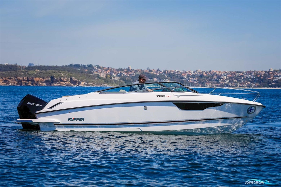 A white Flipper 700 DC boat with a Mercury engine, cruising on clear water, with a coastal city visible in the background.
